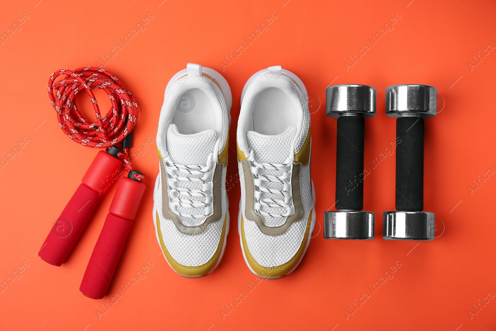 Photo of Flat lay composition of training shoes, dumbbells and jump rope on color background