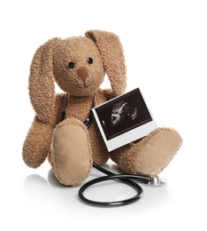 Ultrasound photo of baby and toy rabbit on white background. Concept of pregnancy