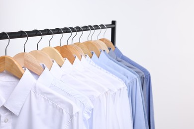 Photo of Dry-cleaning service. Many different clothes hanging on rack against white background, closeup