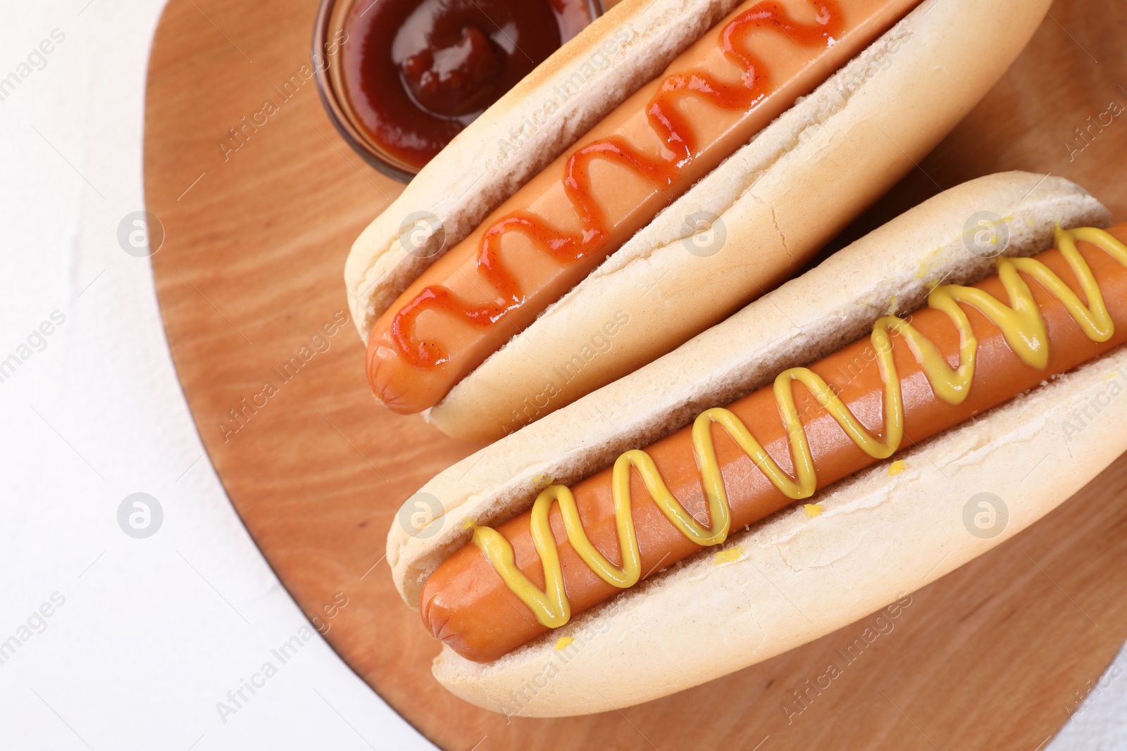 Photo of Tasty hot dogs with ketchup and mustard on white table, top view