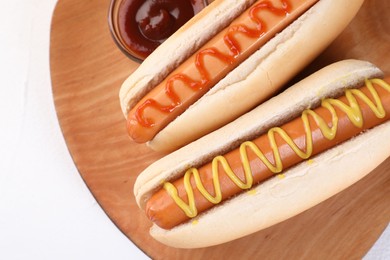 Tasty hot dogs with ketchup and mustard on white table, top view