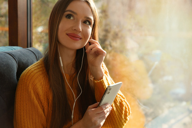 Woman listening to audiobook near window in cafe