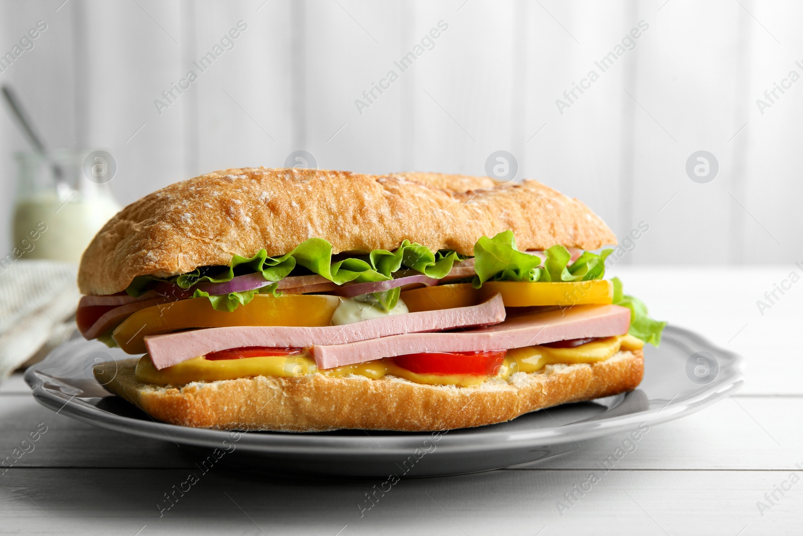 Photo of Tasty sandwich with boiled sausage, cheese and vegetables on white wooden table