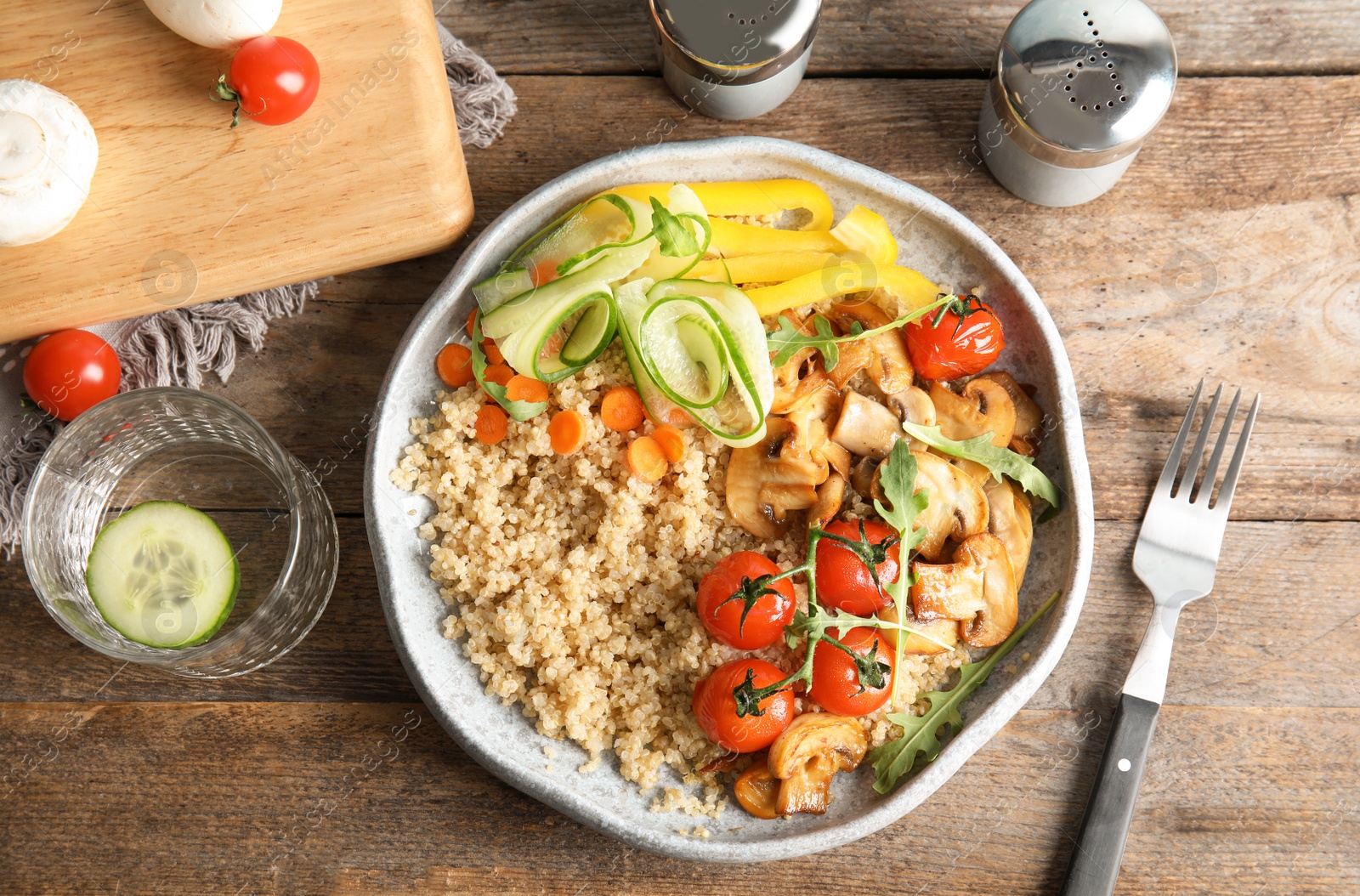 Photo of Plate with healthy quinoa salad and vegetables served on wooden table, top view