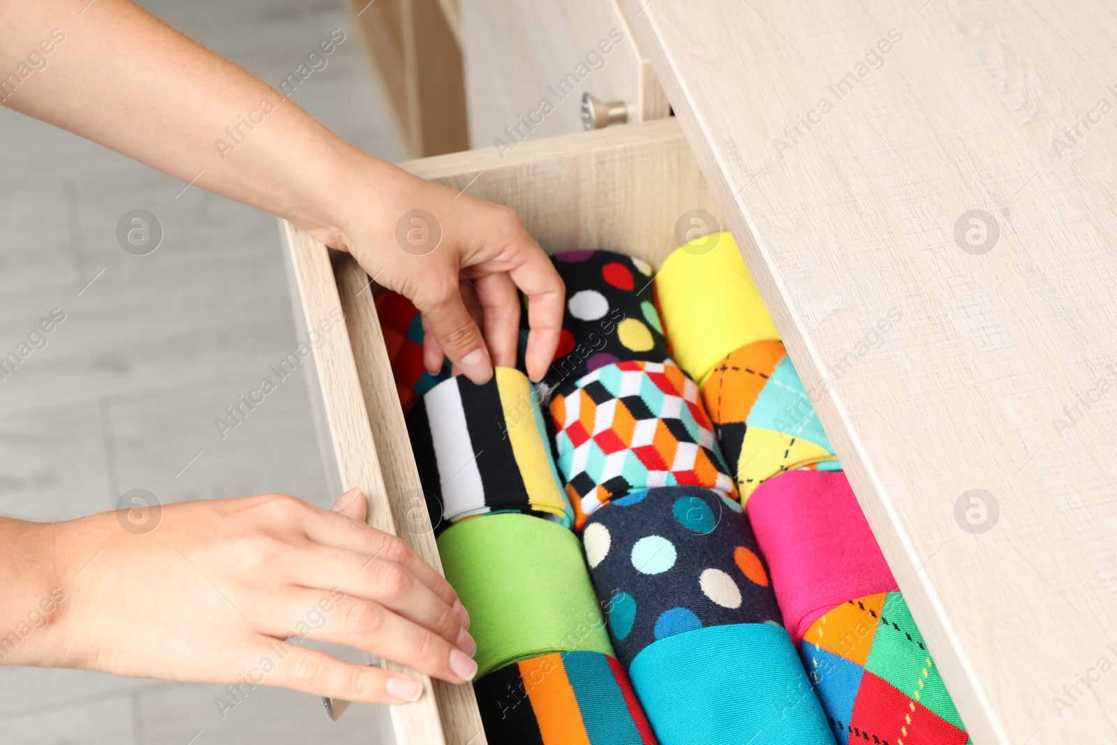 Photo of Woman opening drawer with different colorful socks indoors, closeup