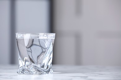 Photo of Glass of clean water on white marble table indoors, space for text
