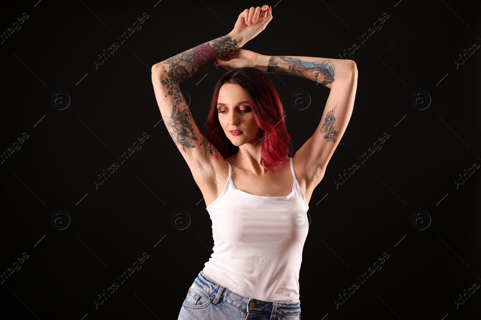 Photo of Beautiful woman with tattoos on arms against black background