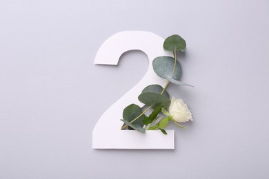 Photo of Paper number 2, flower and eucalyptus branch on light grey background, top view