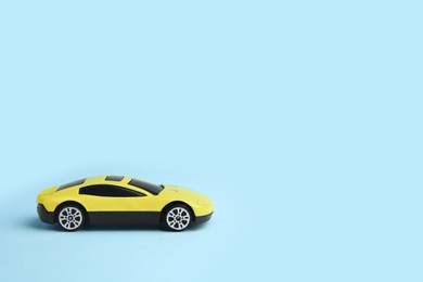 Photo of One yellow car on light blue background, space for text. Children`s toy