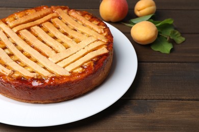 Tasty apricot pie and fresh fruits on wooden table