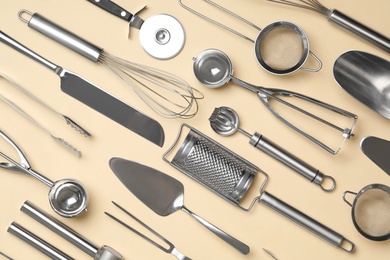 Photo of Set of modern cooking utensils on beige background, flat lay