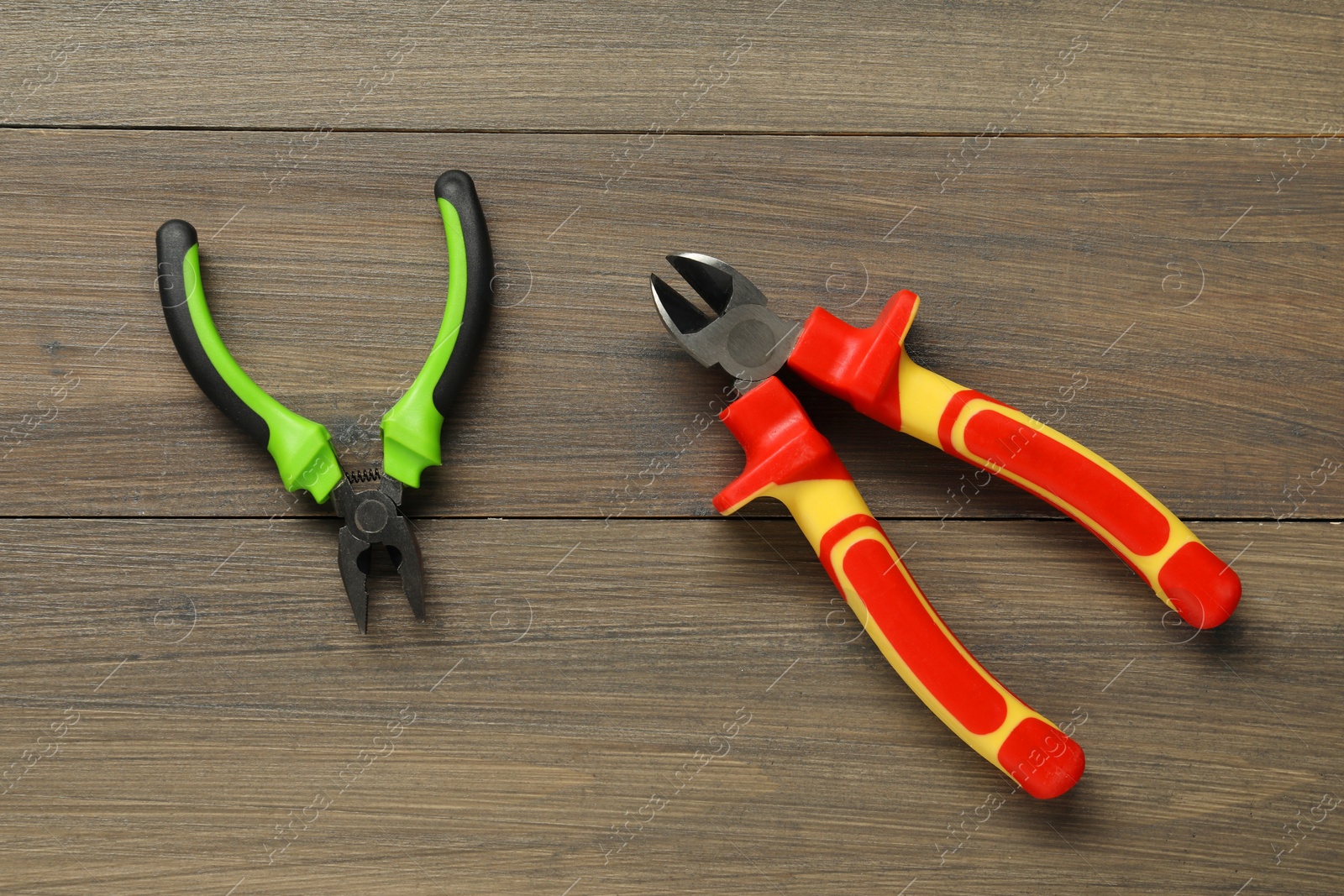 Photo of Two pliers on wooden table, flat lay