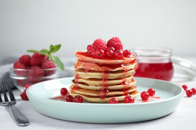 Photo of Delicious pancakes with fresh berries and syrup on white table