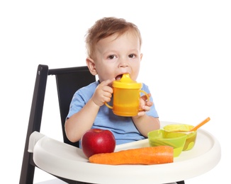 Photo of Adorable little child having breakfast in highchair against white background. Healthy baby food