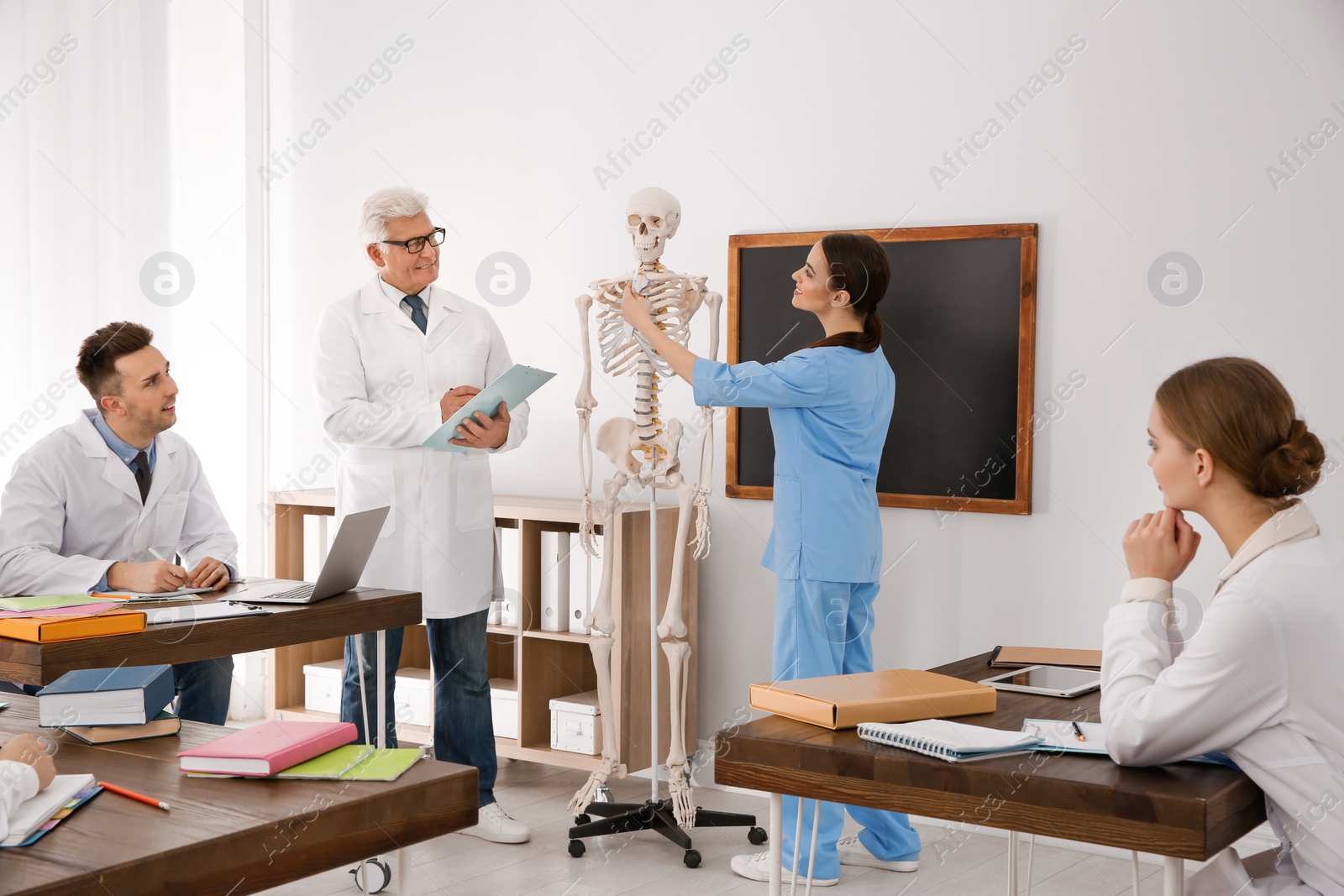 Photo of Medical students and professor studying human skeleton anatomy in classroom