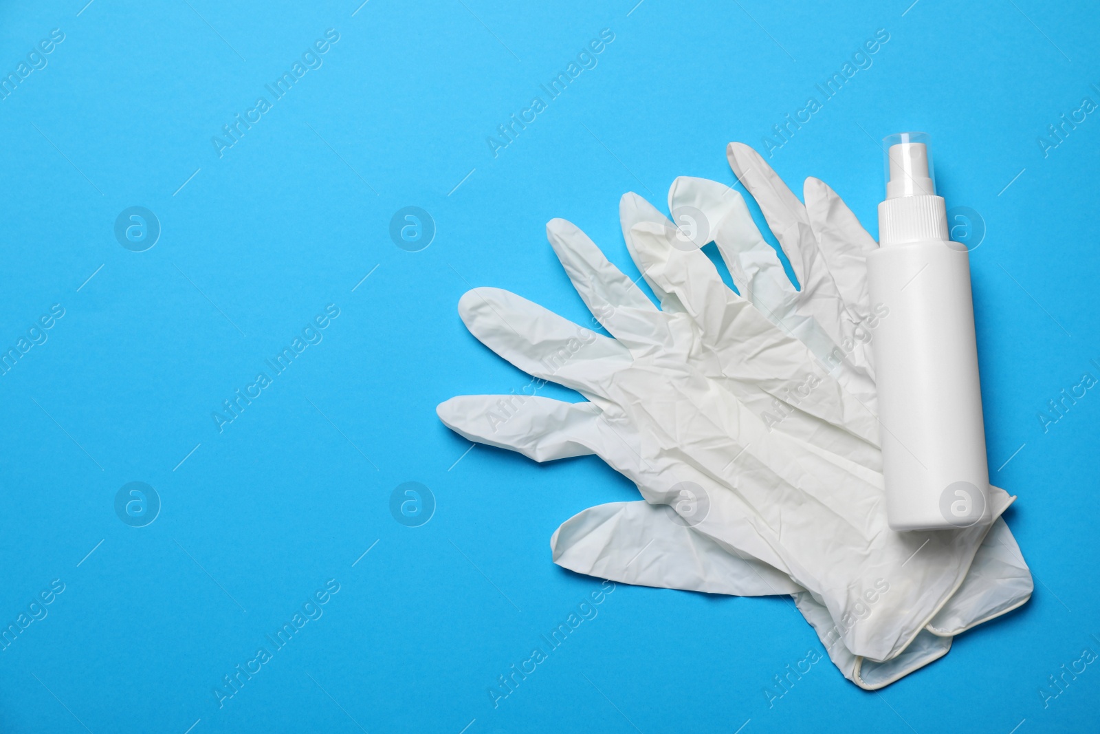 Photo of Medical gloves and hand sanitizer on light blue background, flat lay with space for text. Safety equipment