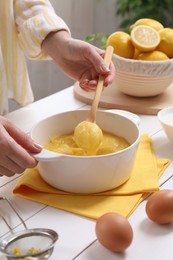 Photo of Woman cooking lemon curd at white wooden table, closeup