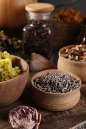 Many different dry herbs and flowers on wooden table