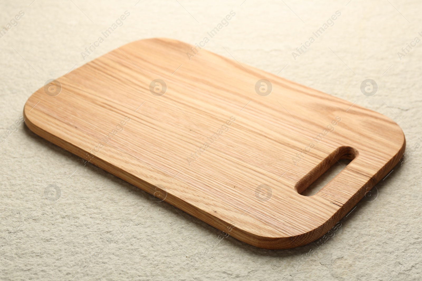 Photo of Wooden cutting board on beige table, closeup