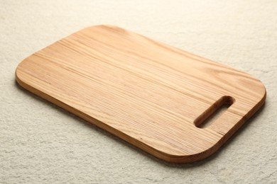 Photo of Wooden cutting board on beige table, closeup