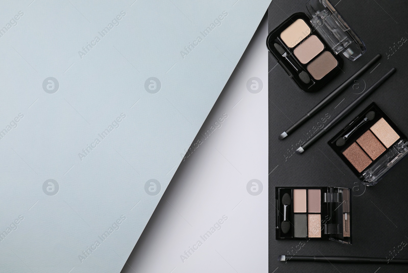 Photo of Different eye shadow palettes and professional makeup brushes on colorful background, flat lay. Space for text
