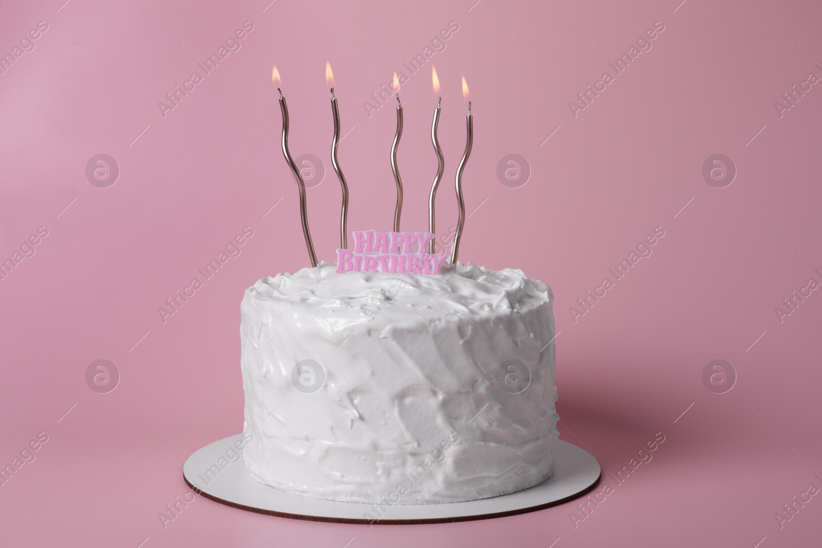 Photo of Delicious cake with cream and burning candles on pink background