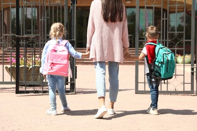 Young mother taking her little children to school outdoors