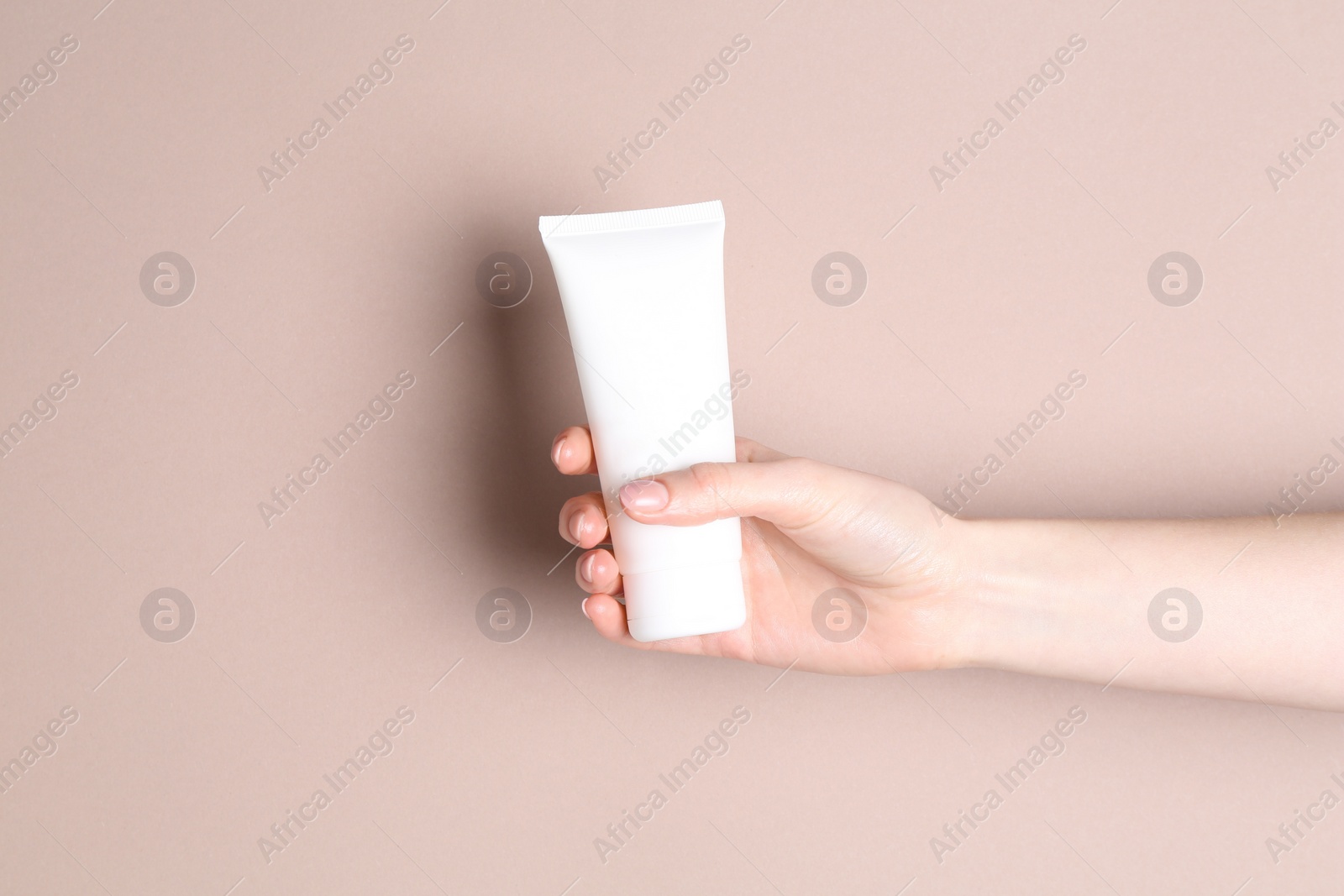 Photo of Woman with tube of cream on beige background, closeup