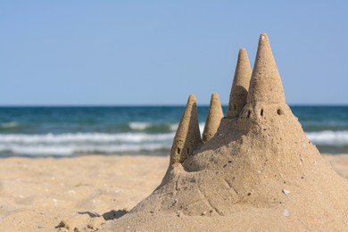 Photo of Beach with sand castle near sea on sunny day. Space for text