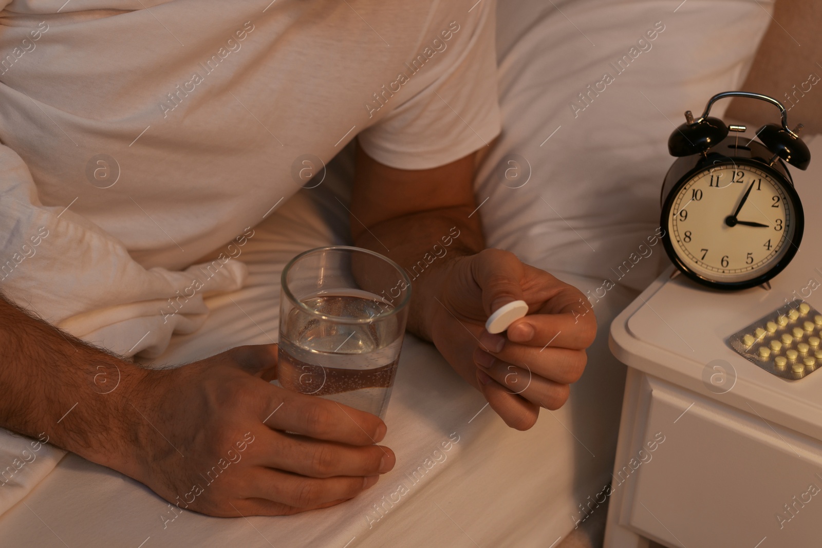 Photo of Man suffering from insomnia taking pill in bed at night, closeup