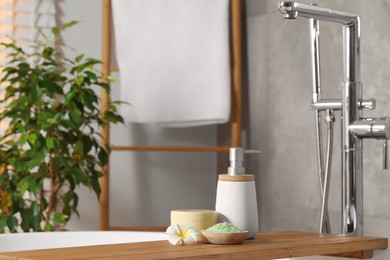 Spa products and beautiful flower on wooden tub tray in bathroom