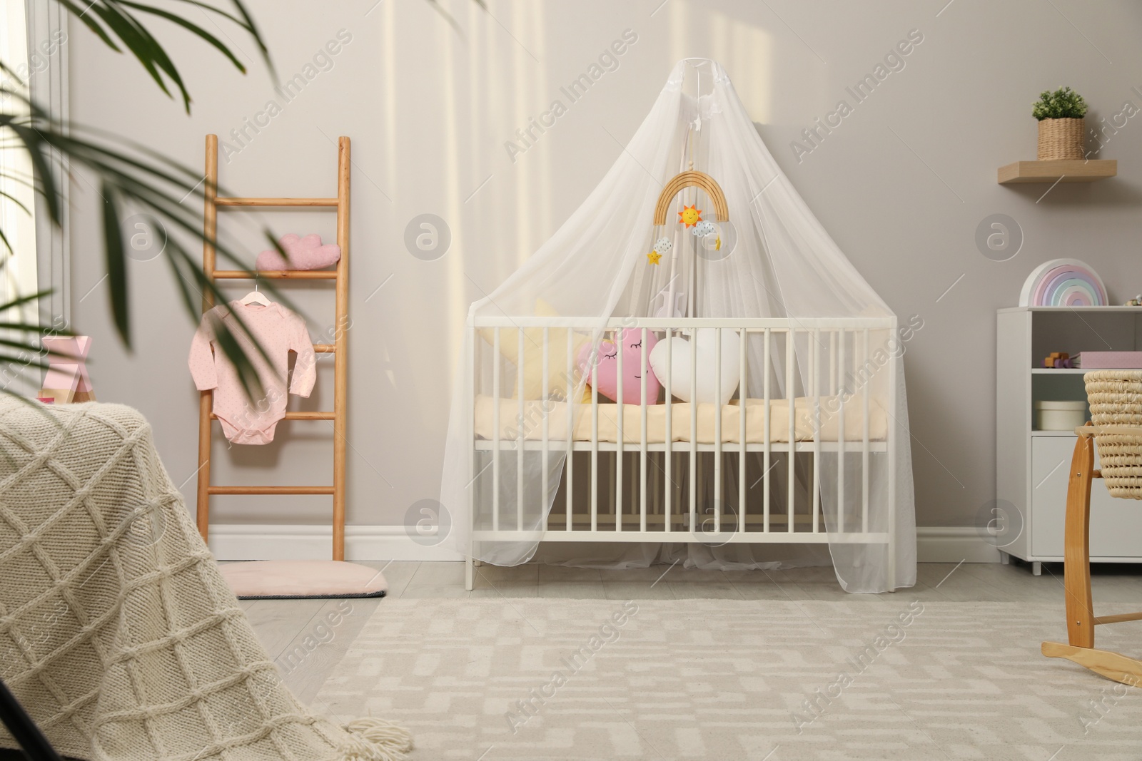 Photo of Cozy baby room with crib and other furniture. Interior design