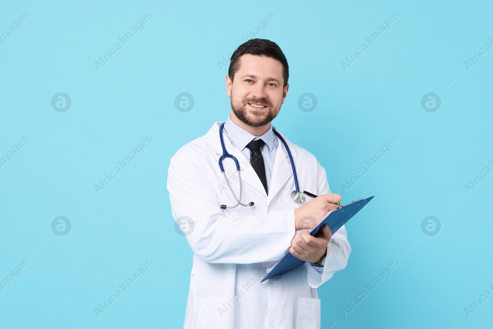 Photo of Smiling doctor with clipboard on light blue background