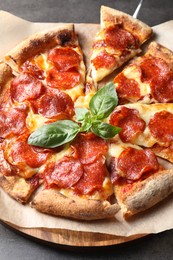 Photo of Tasty pepperoni pizza with basil on grey table