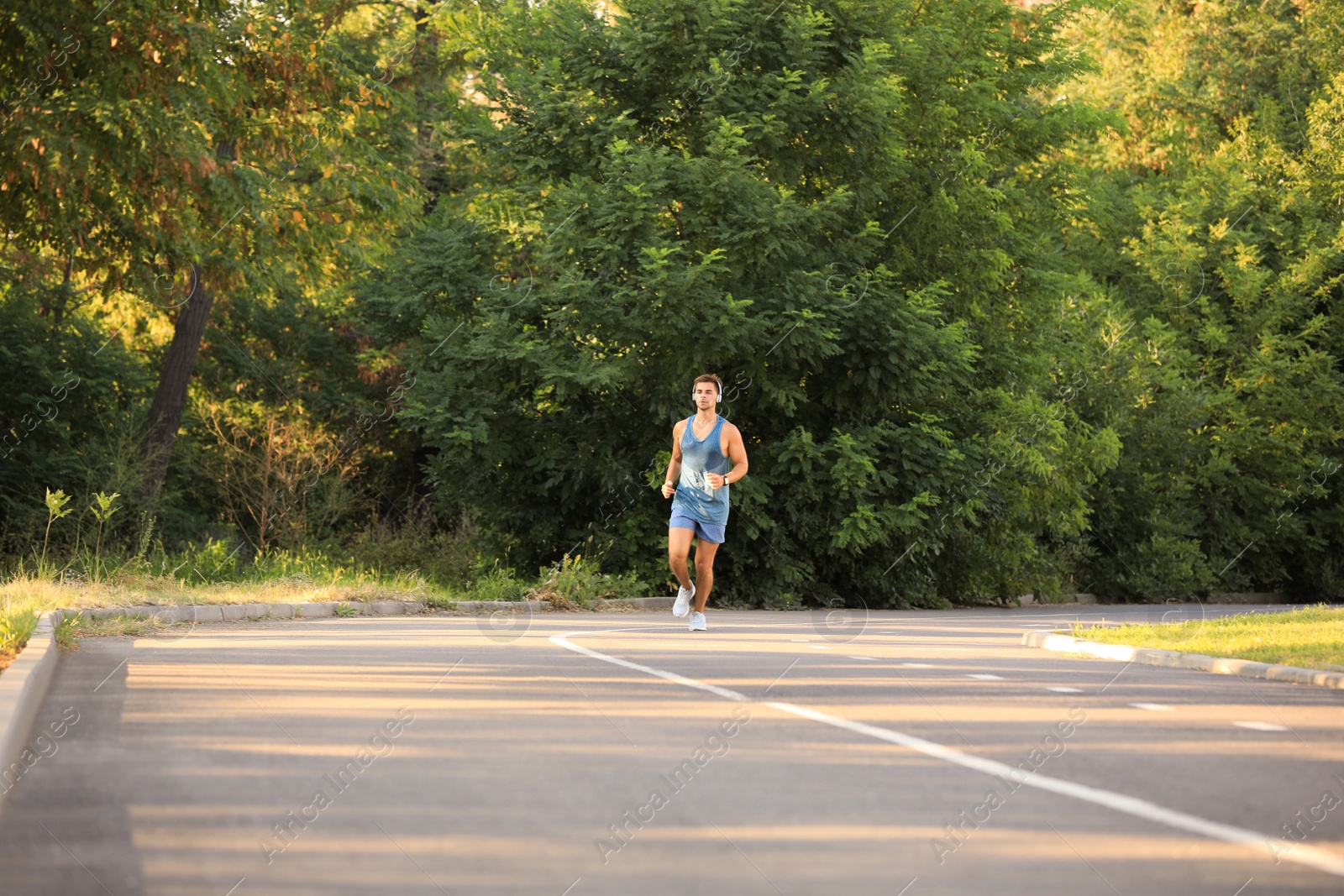 Photo of Young man with headphones running in park