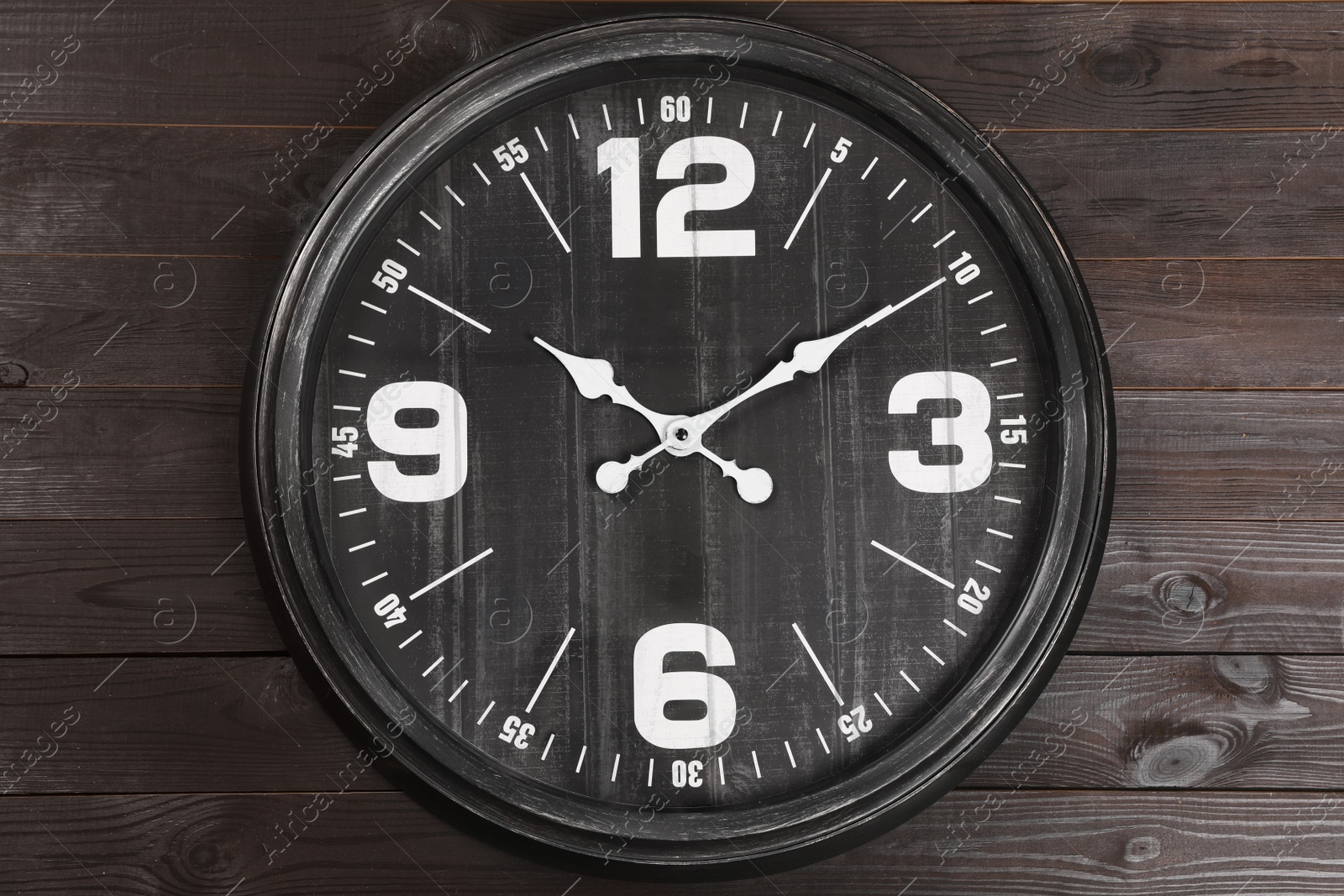 Photo of Stylish analog clock hanging on wooden wall