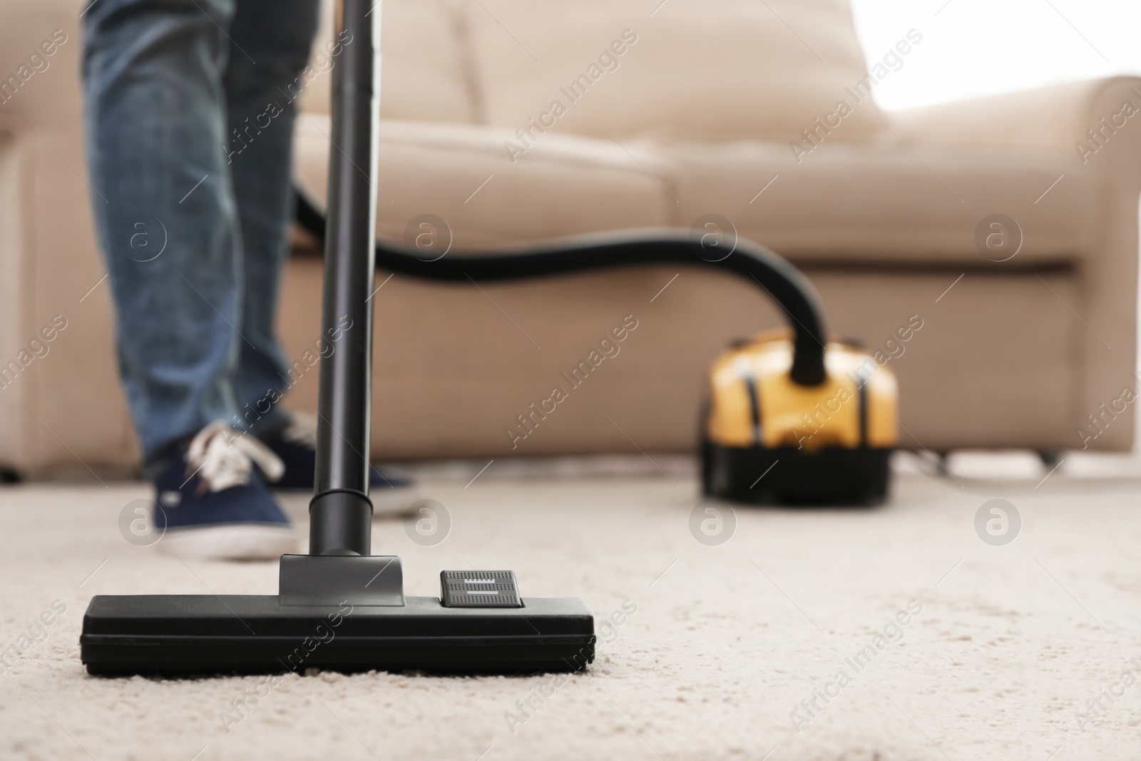 Photo of Young man using vacuum cleaner at home, closeup