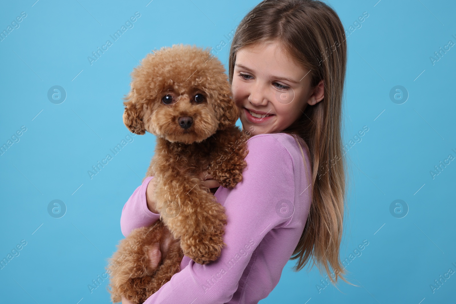 Photo of Little child with cute puppy on light blue background. Lovely pet