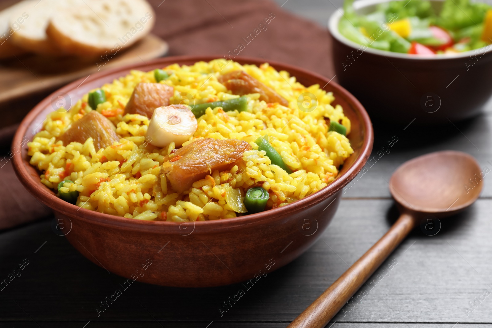 Photo of Delicious pilaf with chicken meat on wooden table