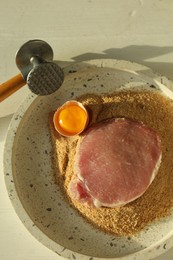 Photo of Cooking schnitzel. Raw pork chop, meat mallet and ingredients on white wooden table, flat lay