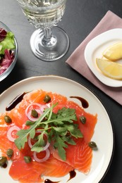 Photo of Delicious salmon carpaccio served on black table, above view