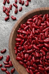 Photo of Raw red kidney beans with wooden bowl on grey table, flat lay