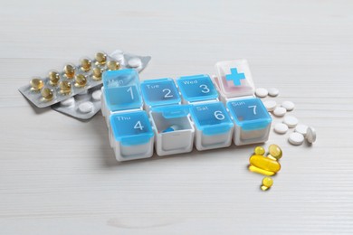 Weekly pill box with medicaments on white wooden table