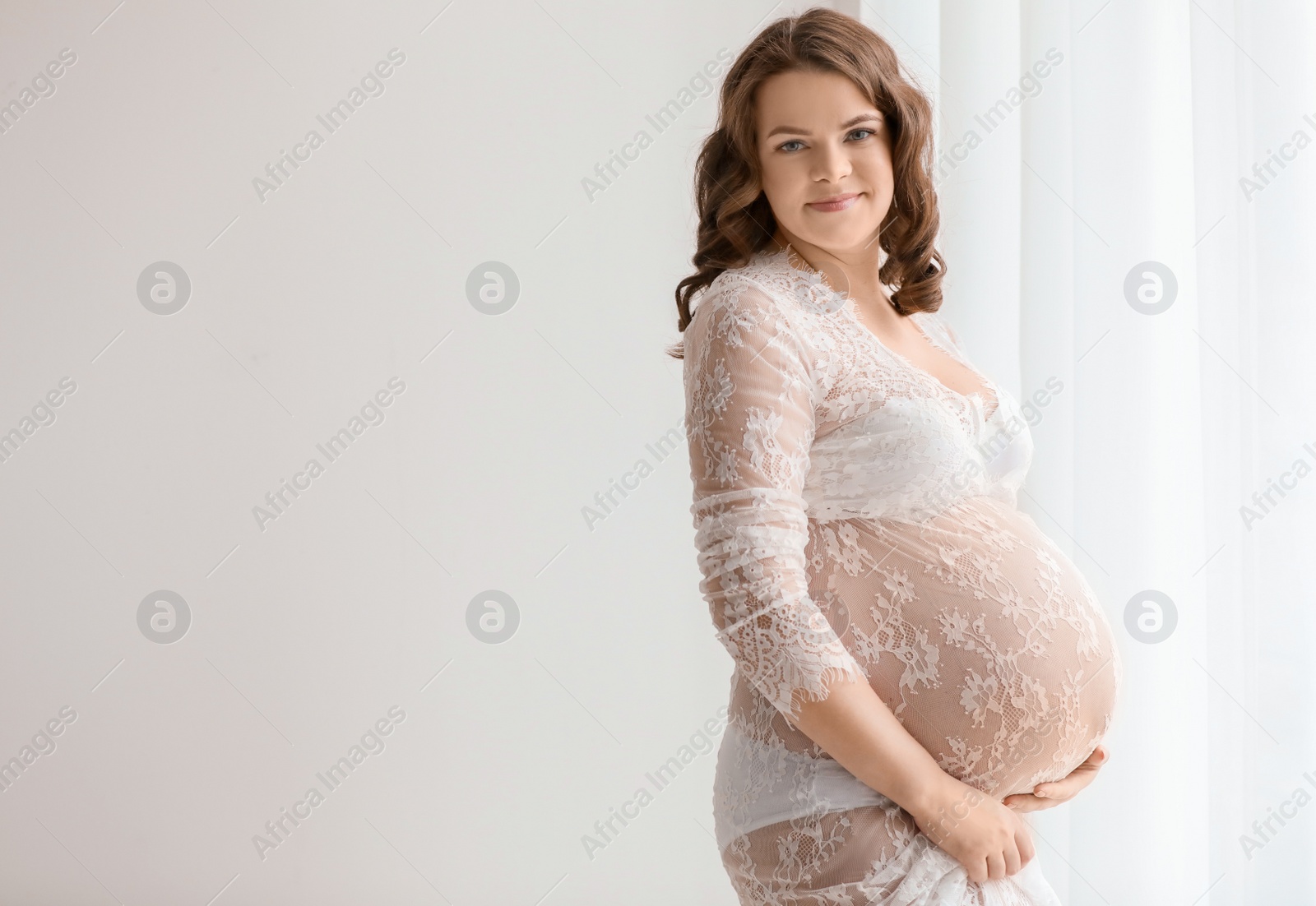 Photo of Young pregnant woman in elegant dress on light background