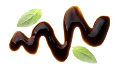 Balsamic glaze and basil leaves on white background, top view