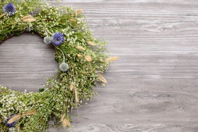 Beautiful wreath made of wildflowers on wooden background, above view. Space for text