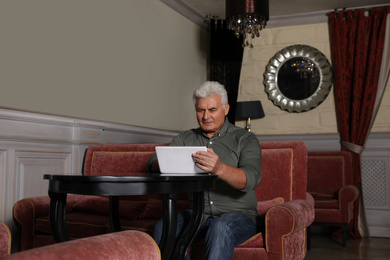 Photo of Senior business owner with tablet in his restaurant