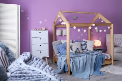 Photo of Child's room interior with comfortable bed and garland