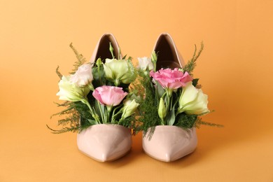 Photo of Stylish women's high heeled shoes with beautiful flowers on pale orange background