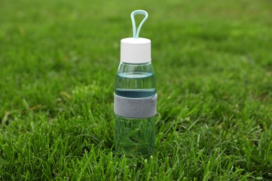 Glass bottle of fresh water in green grass